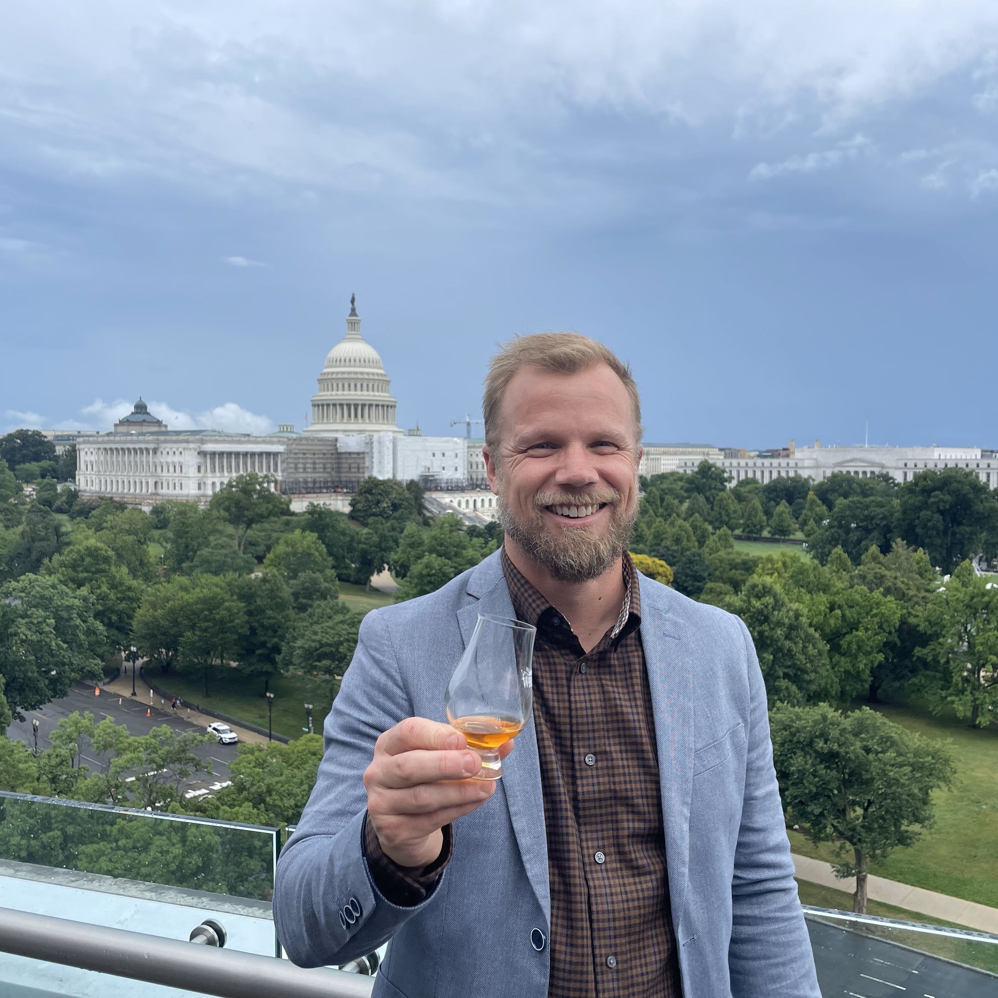 Leigh holding a glass of Backwoods whisky at Capitol Hill