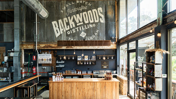 Bar interior with 'Backwoods Distilling' sign on the wall