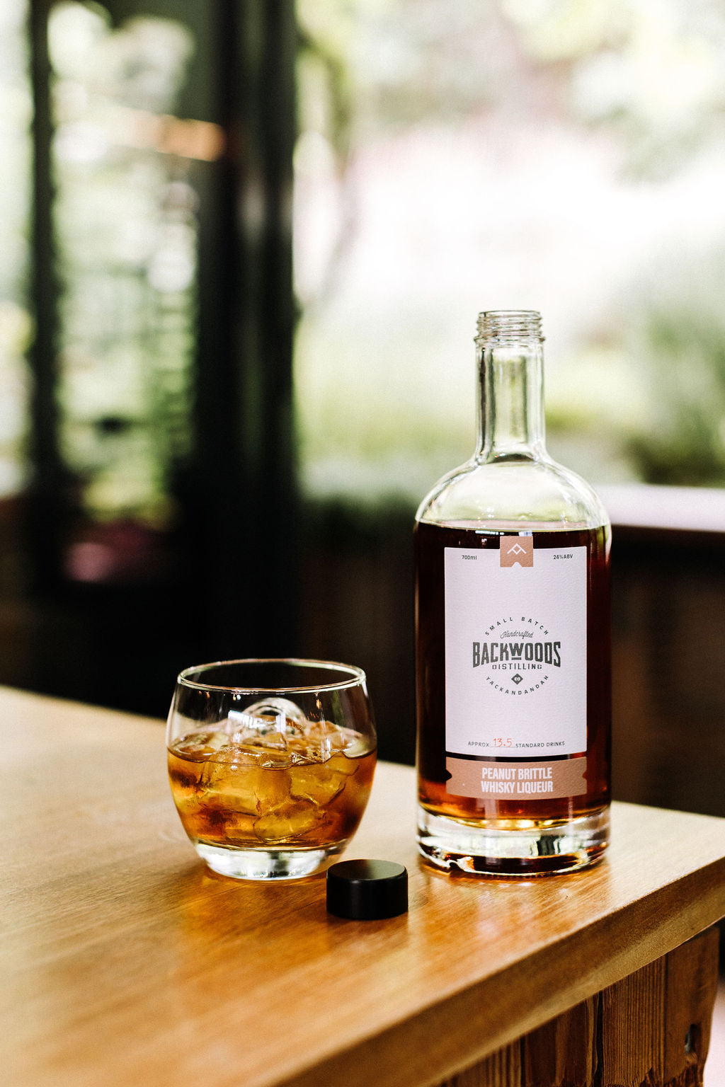 Bottle of Backwoods whisky liqueur with a glass on a wooden surface