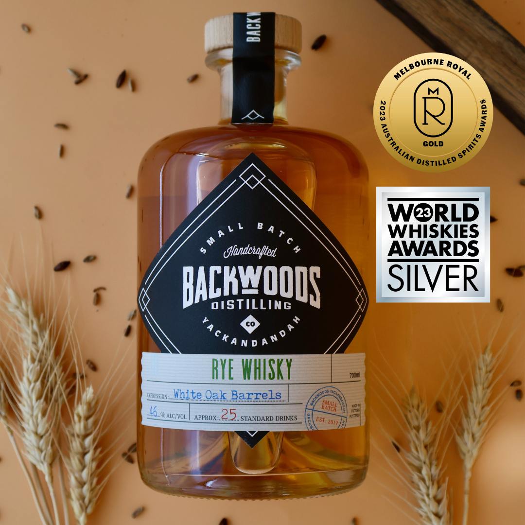 Backwoods Distilling Rye Whisky bottle with awards on a textured background